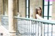 A woman in a white dress standing on a balcony.