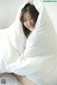 A woman laying in bed under a white blanket.