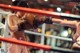 A woman in a boxing ring with a man in the background.