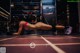 A woman in a pink bikini doing push ups in a gym.