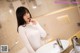 A woman in a white dress standing in front of a sink.