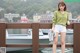 A woman standing on a wooden bridge next to a body of water.