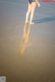 A woman in a bikini walking on the beach.