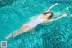 A woman floating in a swimming pool with her arms outstretched.